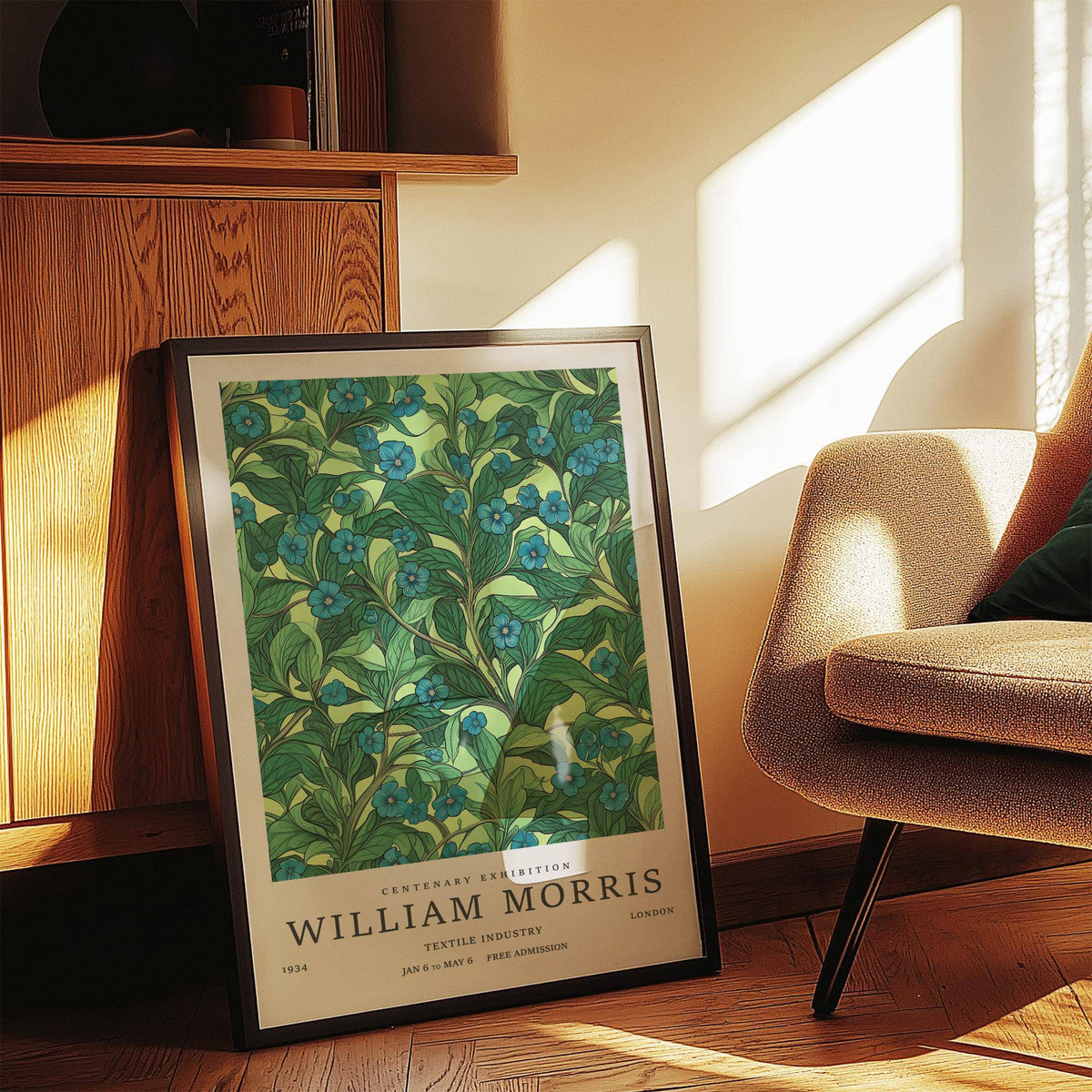 Green wall art for living room leaning on floor with blue flowers and dark frame beside armchair