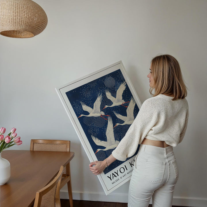 Framed Blue and White Prints with flying white cranes held by a woman in a dining room