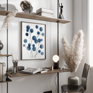 Watercolor flower wall art with blue botanical blooms above a wooden desk with a lamp in a home office