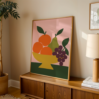 Fruit bowl print with oranges and grapes leaning on a wooden sideboard in a warm living room