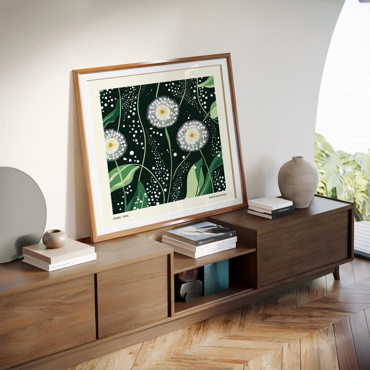 Print leaning on a shelf showing dandelion seed heads in green and white tones with wooden cabinets