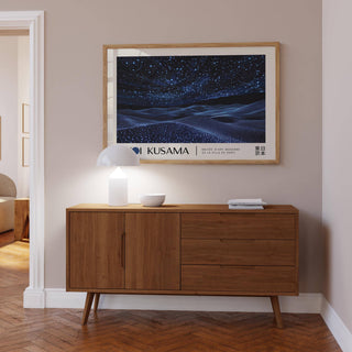 Night Sky wall art with starry night sky over waves above a wooden sideboard with a white lamp