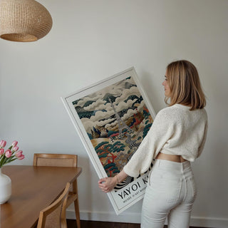 Framed surreal Eiffel Tower Art held by a woman with an off white sweater by a dining table