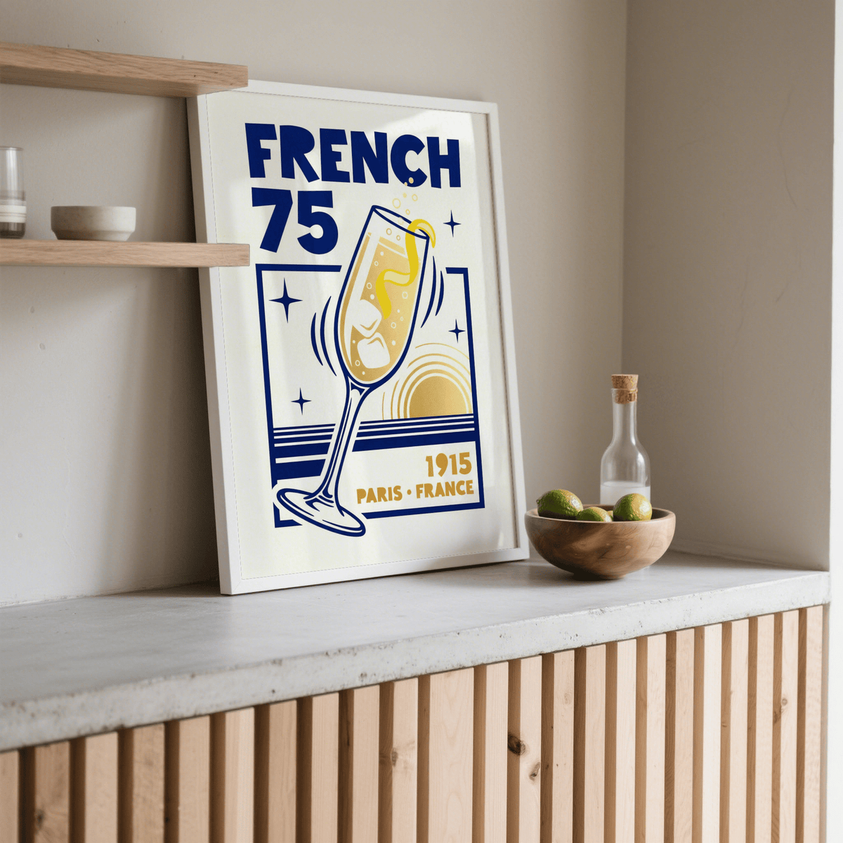French 75 Poster print leaning on shelf with wooden bowl of limes nearby in a neutral room