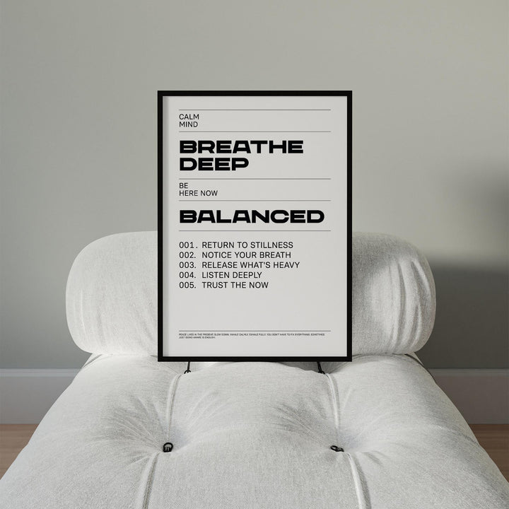 Framed Zen Quotes Breath print with black text on white held on a pale armchair