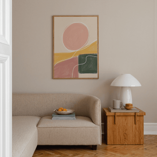 Modern Abstract Print hanging above beige sofa with wooden side table and white lamp