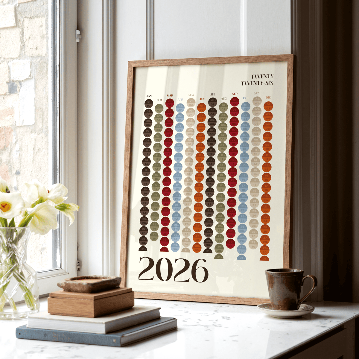 Framed Big Calendar for Wall leaning on a marble surface with books and a cup nearby