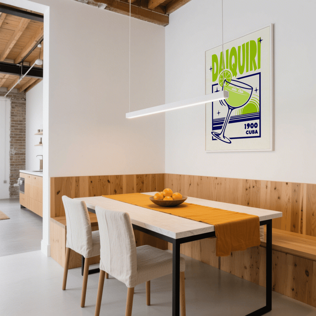 Daiquiri art print on wall above dining table with wooden panel and bowl of oranges