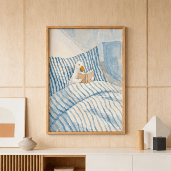 Duck reading art print of a duck reading a book in blue striped bedding above a wooden sideboard
