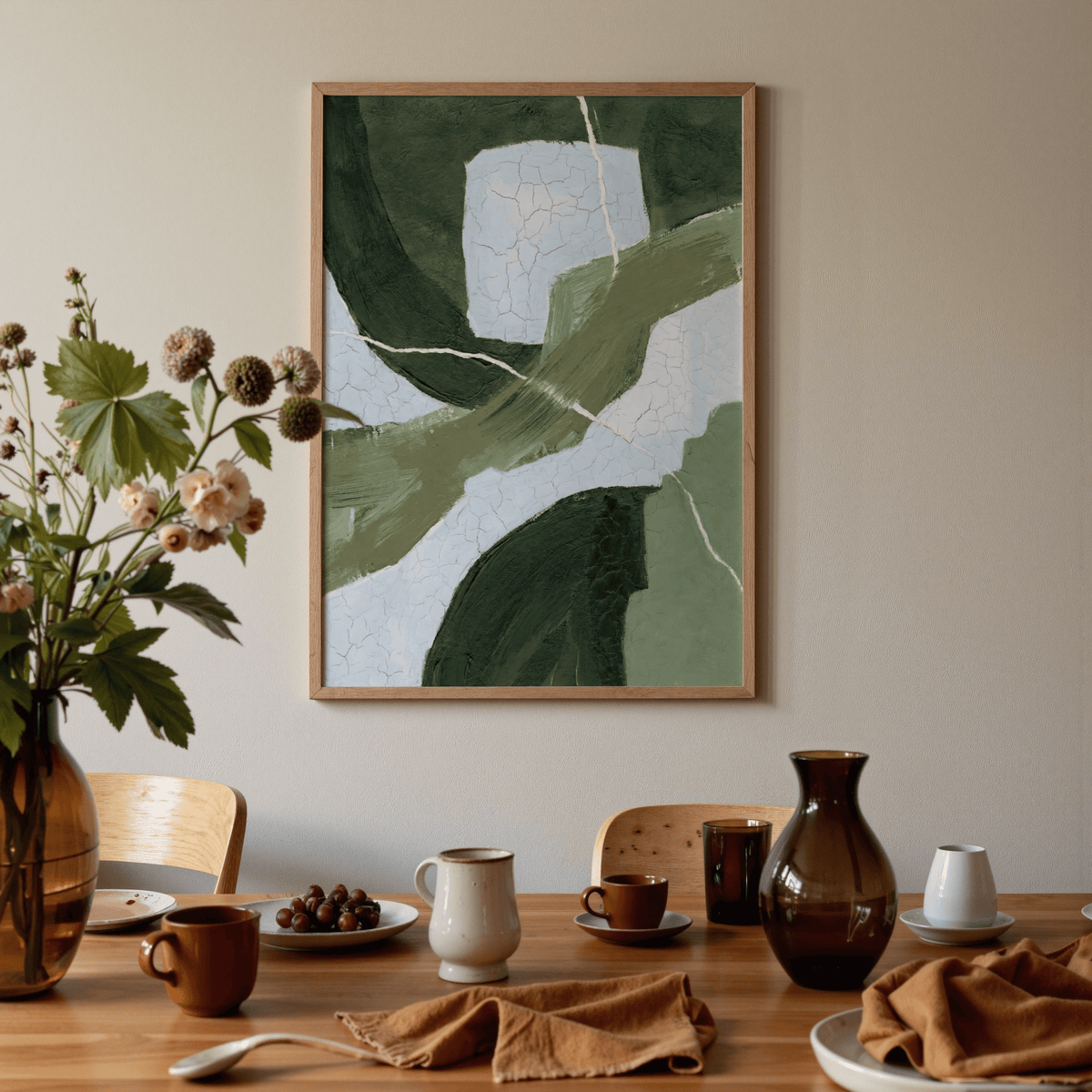 Print on a wall of abstract green shapes in various shades above a dining table with brown crockery