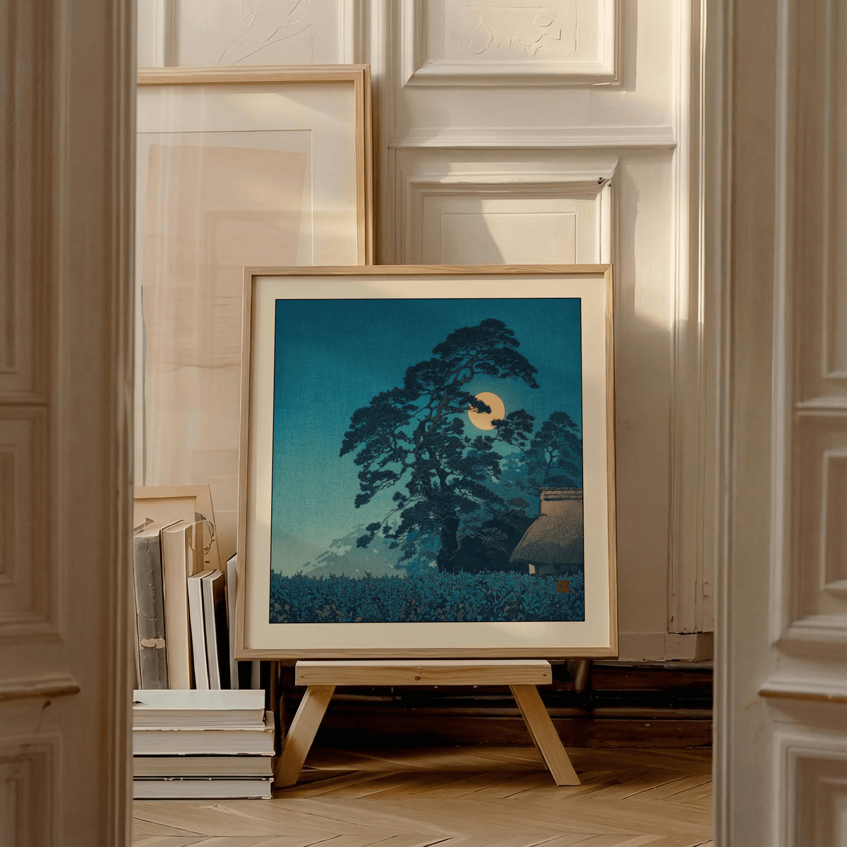 Framed Hasui Kawase Moon Print leaning on a wooden easel with other framed prints around