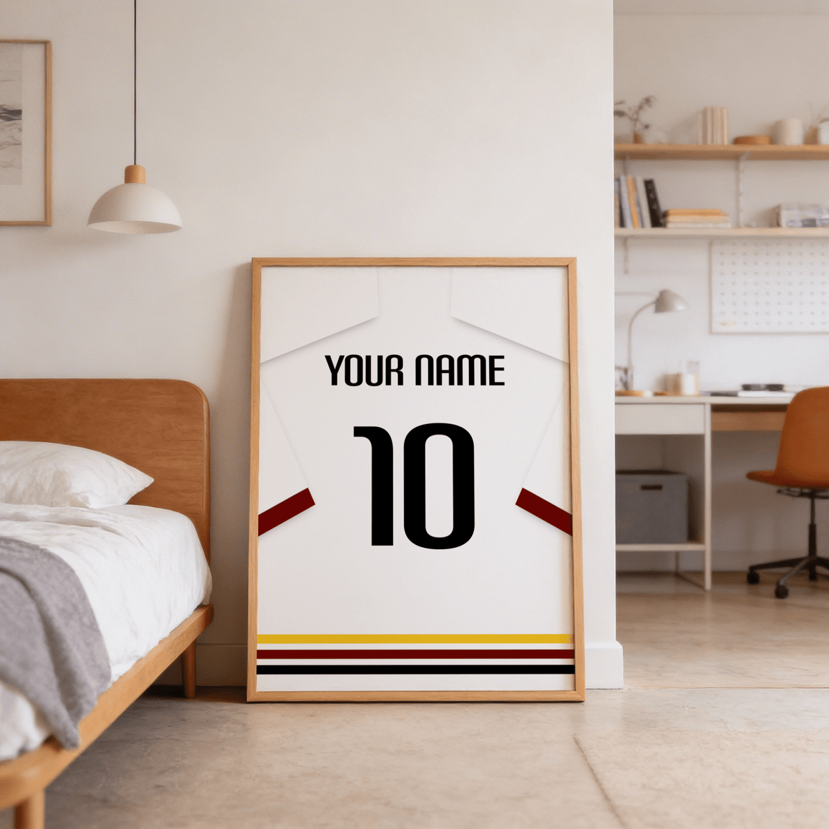 Football Shirt Poster in White with Black Red and Gold Hem Stripes leaning on the floor next to a bed in a bedroom