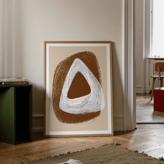 Print leaning on floor with abstract brown and white triangle shapes beside a green side table