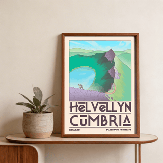 Framed Helvellyn Cumbria wall art of a mountain hiker in blue green and purple tones on a wooden table beside a plant