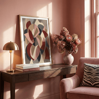 Print leaning on a dark wooden table with books and flowers beside it in a pink living room