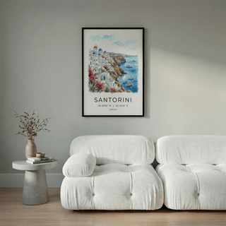 Santorini art print of a watercolour cliffside village above a white sofa with a side table and vase