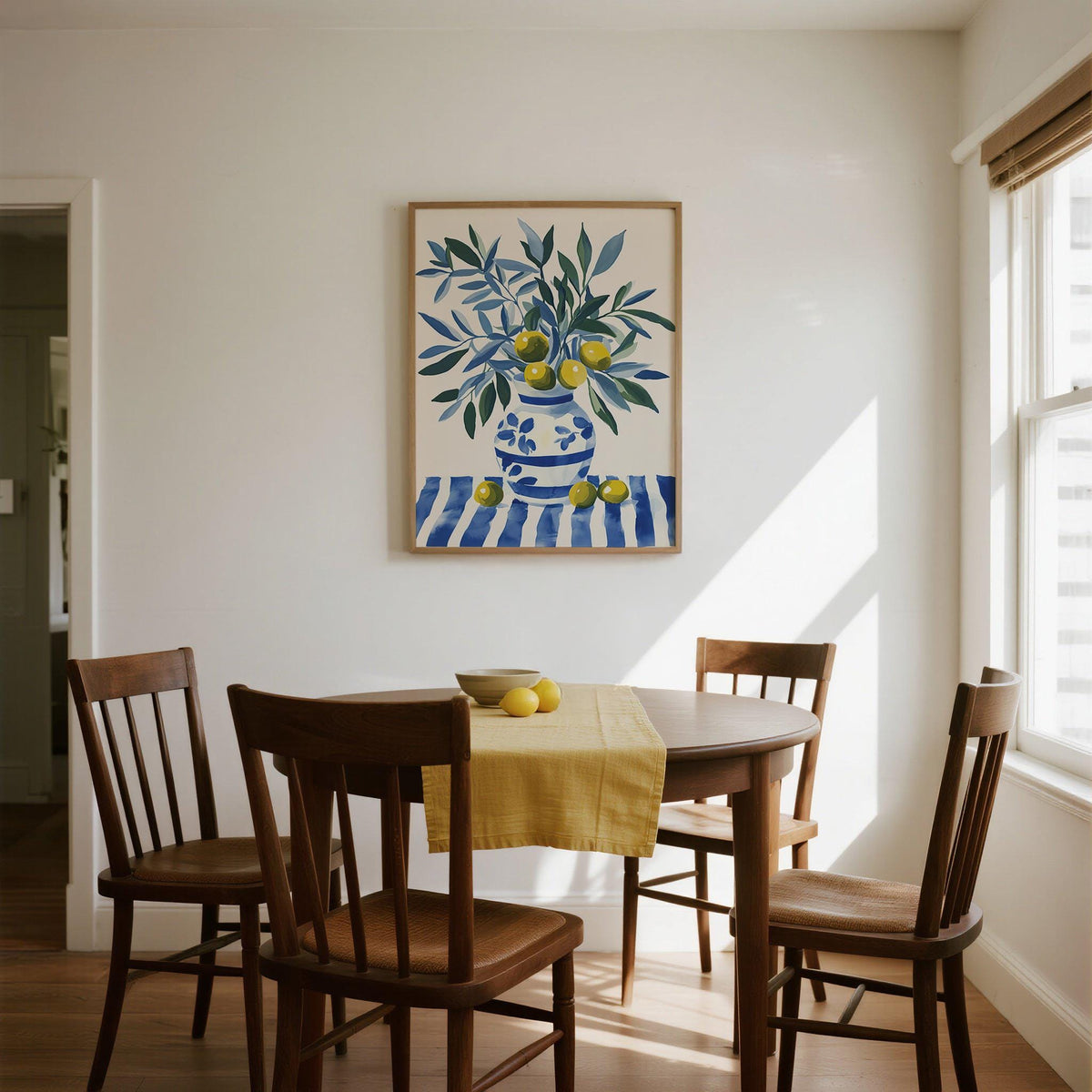 Olive Tree wall art of a blue and green olive branch above a wooden dining table with a yellow runner