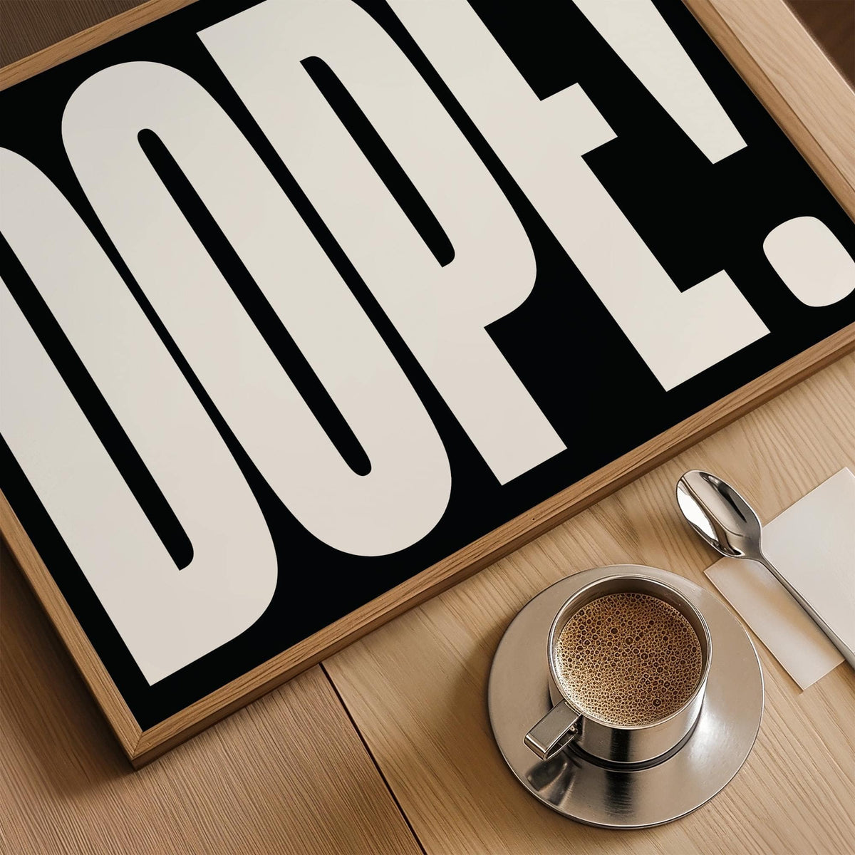 Close-up of bold font poster with large white letters on black and a coffee cup on a wooden table