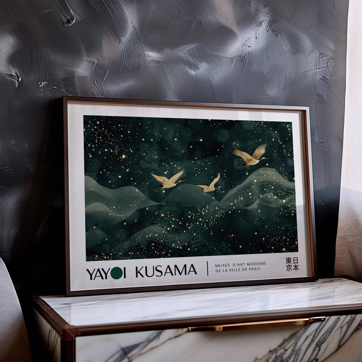 Japanese wall hanging with golden cranes flying over dark green abstract hills and gold speckles leaning on a marble surface