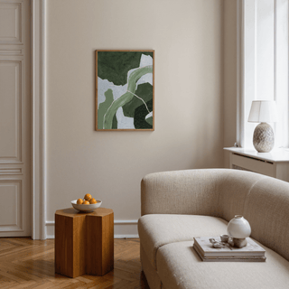 Abstract green art print with curved shapes above a wooden side table in a living room