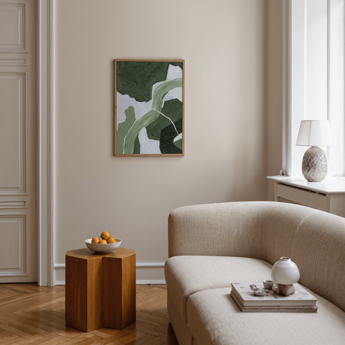 Abstract green art print with curved shapes above a wooden side table in a living room