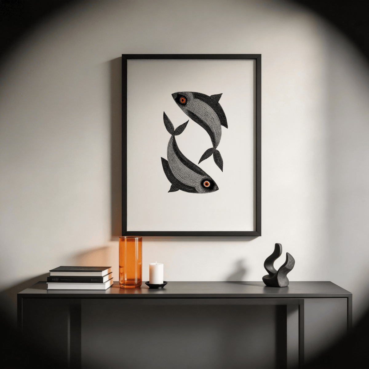 Madhubani Fish wall art of two black fish with red eyes above a side table with books and a candle