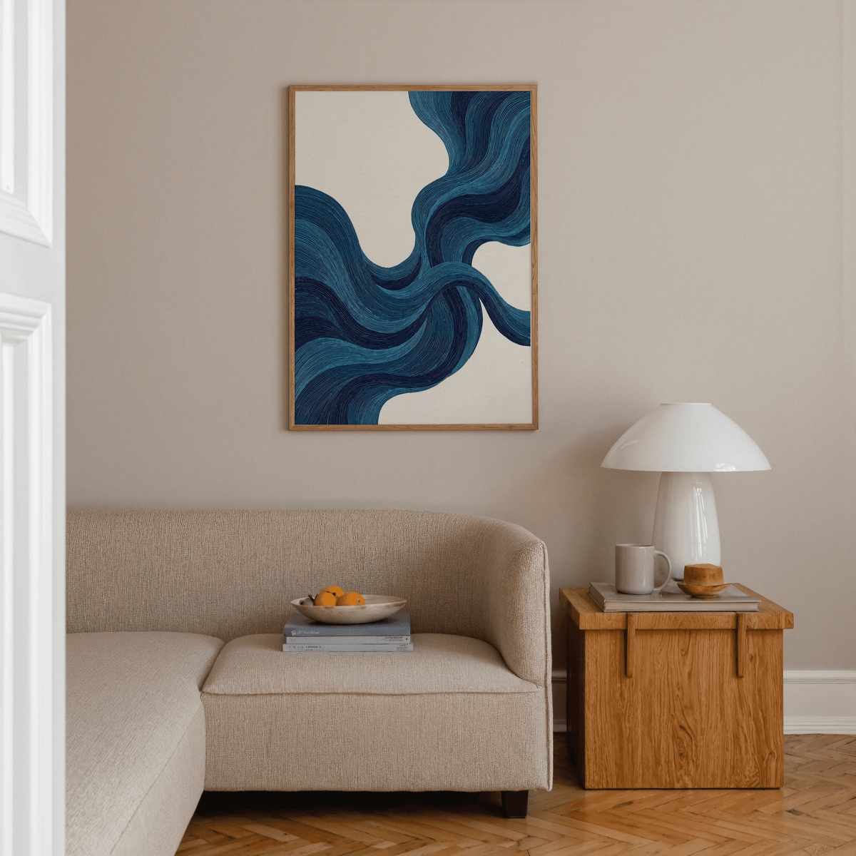 Blue Line Wall Art with flowing blue lines above a beige sofa and a wooden side table with a lamp