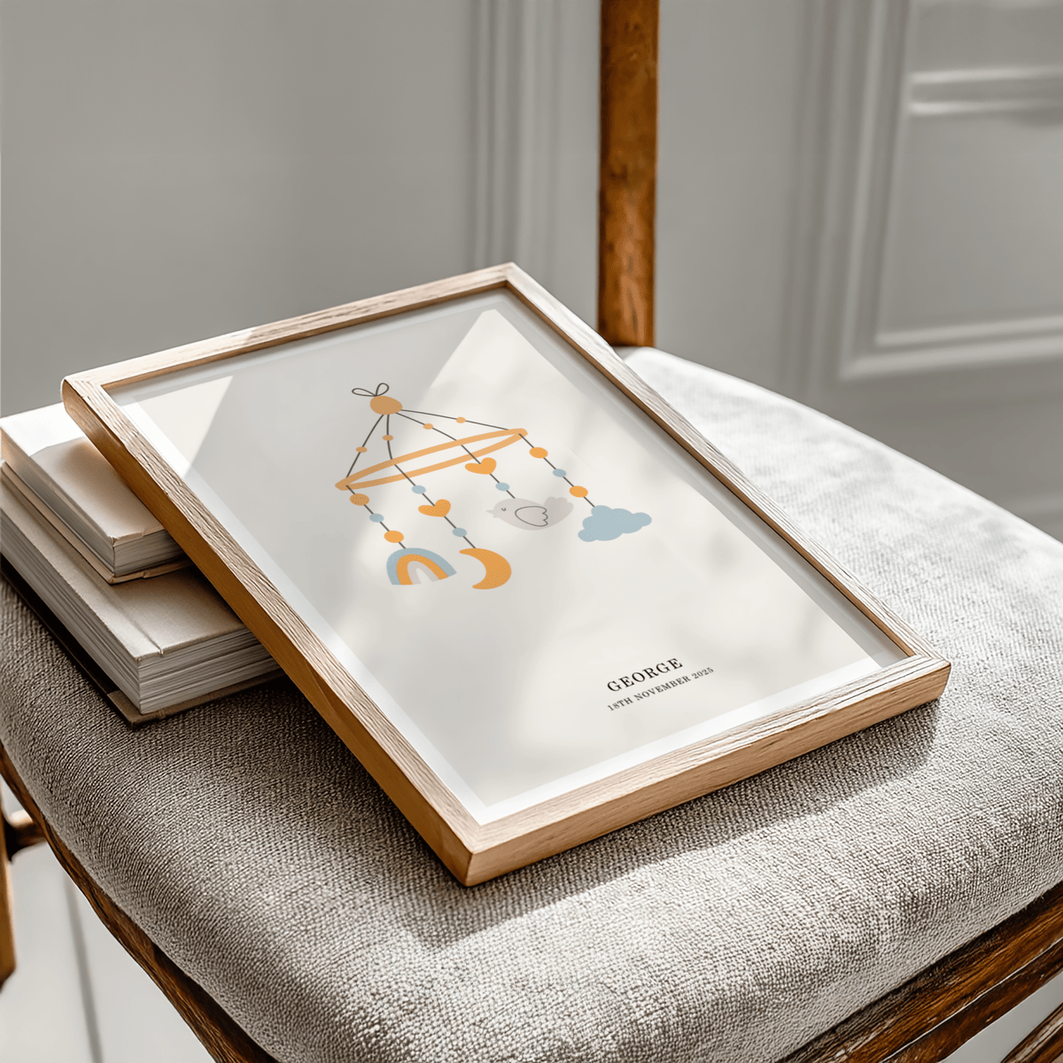Personalised Baby Poster framed close-up on a chair featuring a baby mobile with bird and moon in soft colours