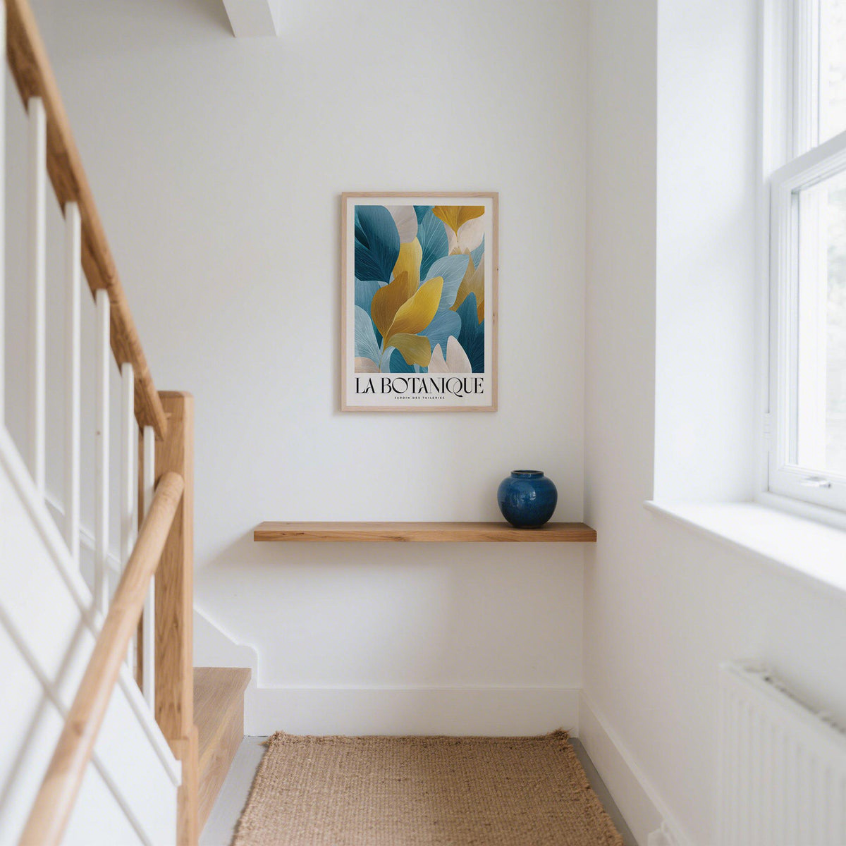 Luxurious wall art of blue and gold leaves in a white hallway above a wooden shelf with a blue vase
