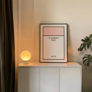 Print leaning with Street Name Family Personal artwork of a pink and white street sign beside a lit round lamp