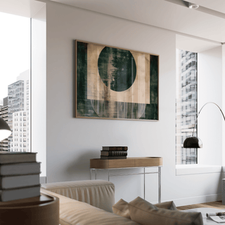 Abstract geometric poster with dark green and beige shapes on a living room wall above a wooden side table with books