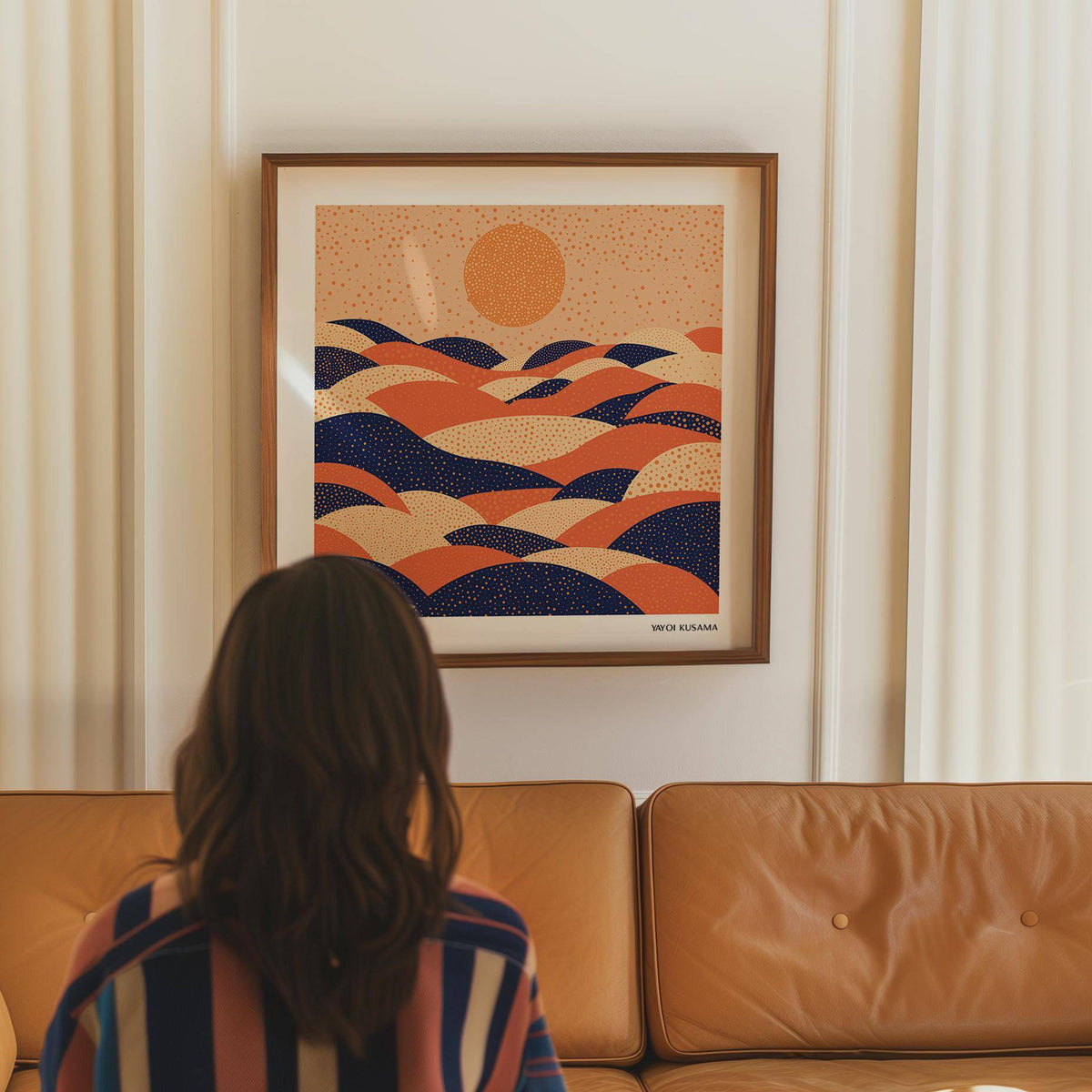 Abstract wall art colorful of abstract hills and sun in orange and navy above a leather sofa