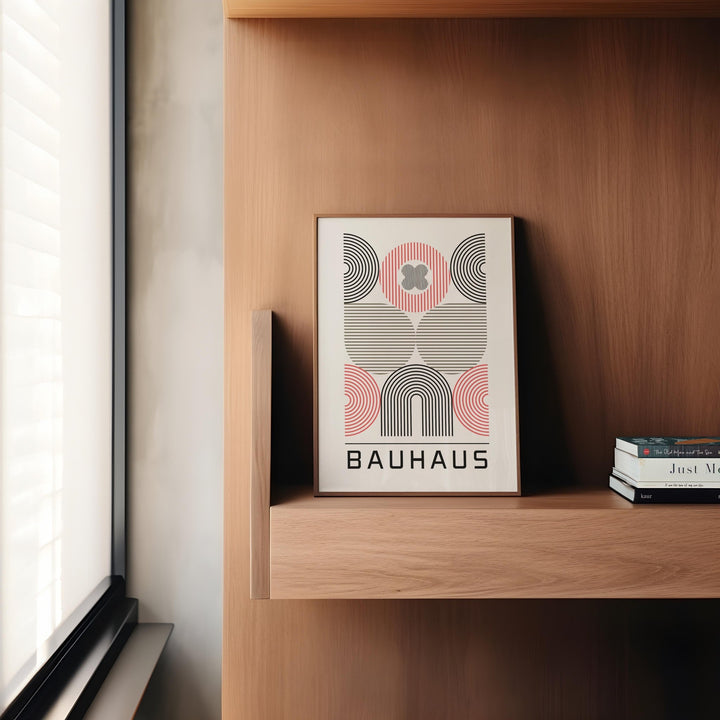 Wall art for home office with abstract geometric shapes in black red and beige leaning on a wooden shelf by a window