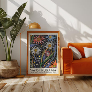 Abstract botanical wall art with dotted flowers in bright colours leaning on the floor next to an orange sofa