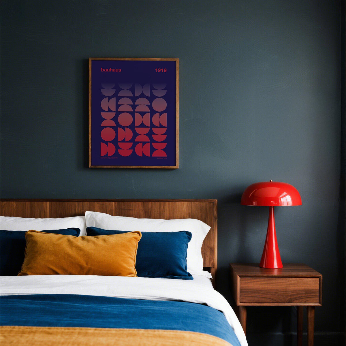 Print on a wall in a bedroom with geometric gradient shapes in red and purple beside a red lamp above a wooden bedside table