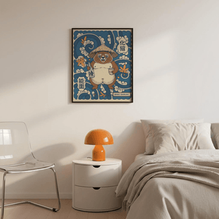 Japanese Tanuki wall art in blue and beige above a white bedside table with an orange lamp