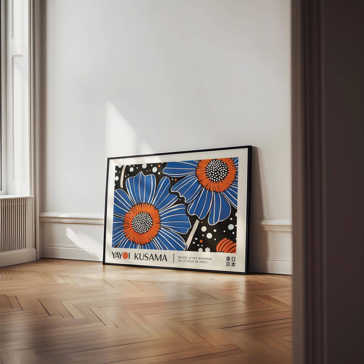 Print leaning with vibrant blue and orange flower illustration on wooden floor near window