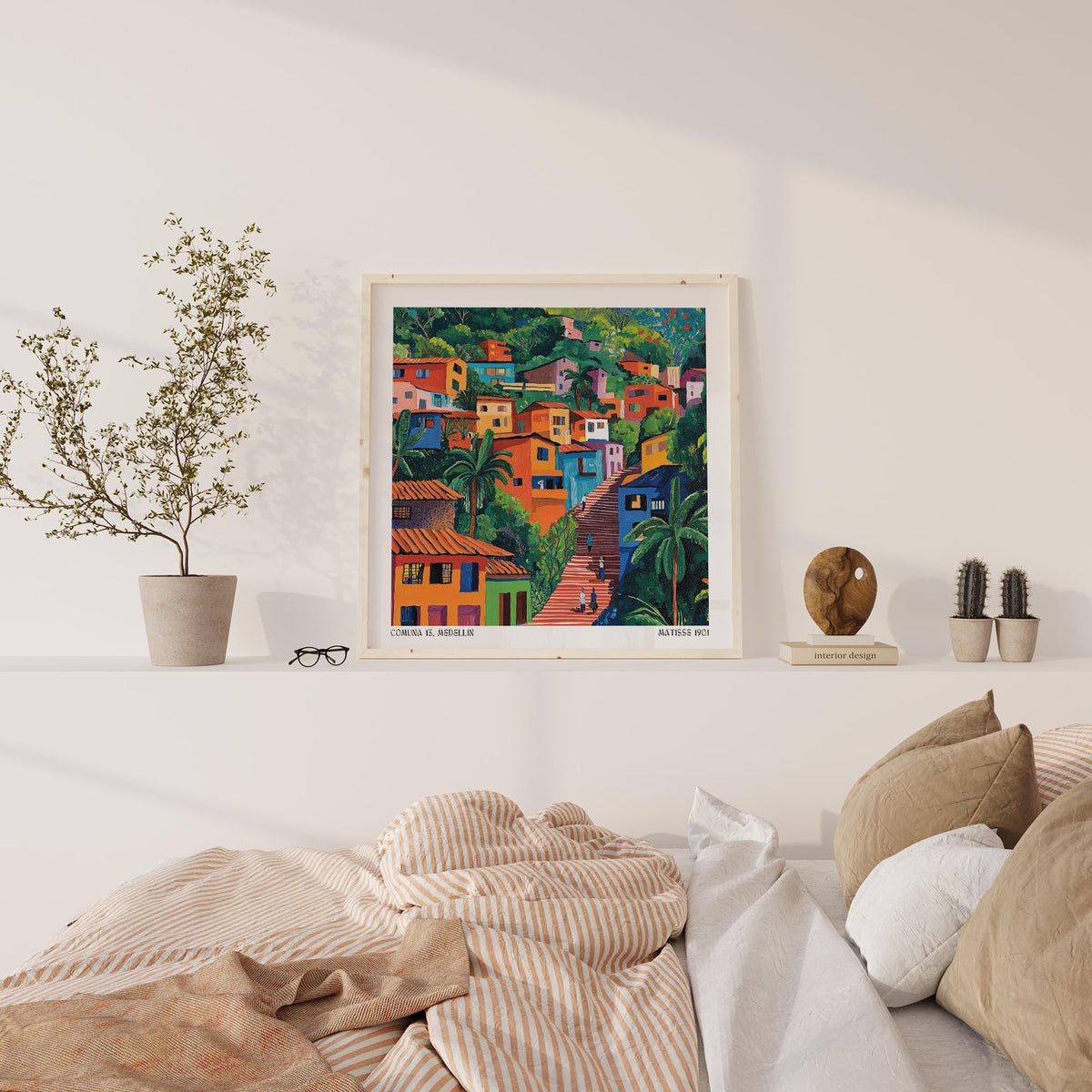 Comuna 13 art print on a white shelf above a bed with brown and white cushions and striped bedding