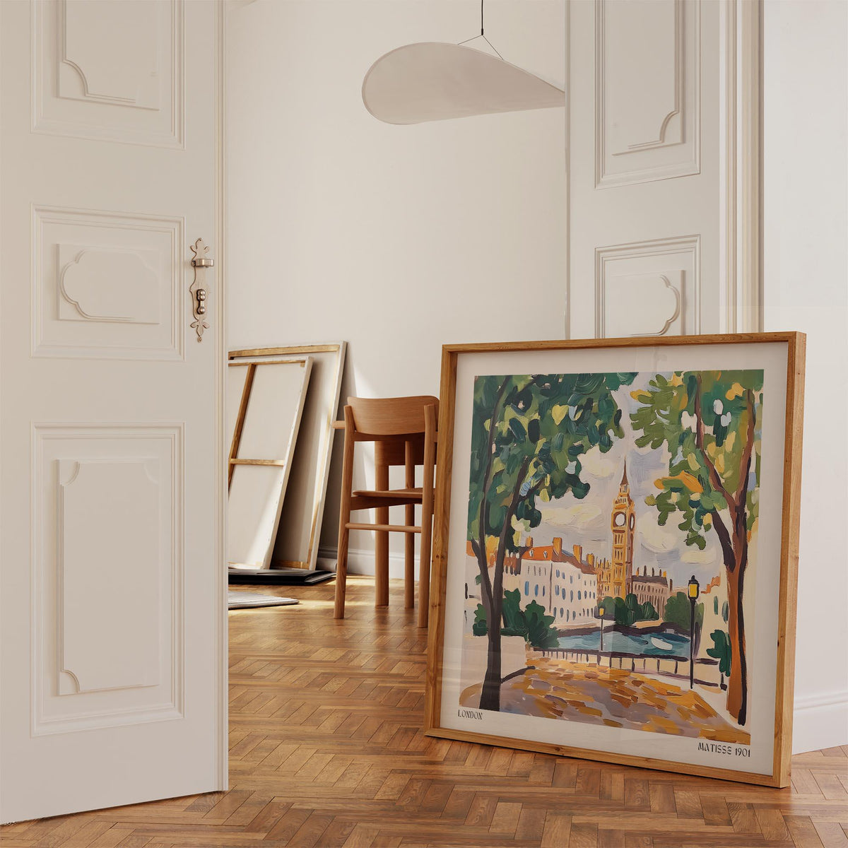 Print leaning on a wooden floor showing an illustration of Big Ben clock tower with green trees in a neutral room