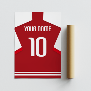 Football shirt poster in red with white sleeves beside a plain brown packaging tube on a grey surface