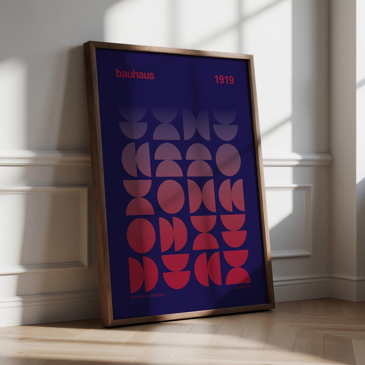Framed Graphic Design Poster with geometric gradient shapes in red and dark blue leaning on a floor by a white wall