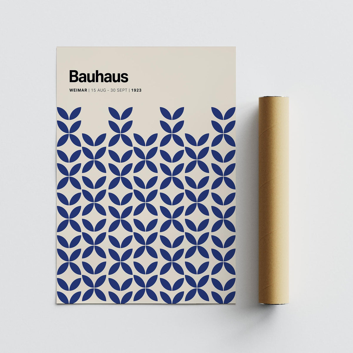 Simple wall art with blue geometric bauhaus pattern next to a brown packaging tube on a grey surface