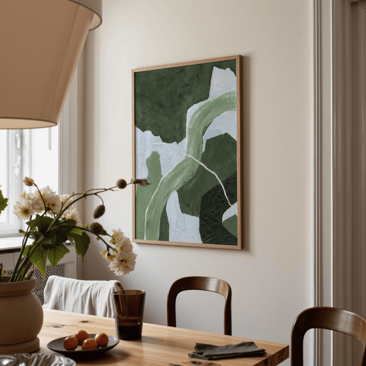 Abstract green art print with textured flow and white lines above dining table with flowers