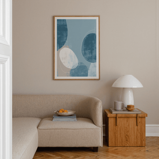 Contemporary Pattern Poster on a beige wall above a sofa with a wooden side table and lamp