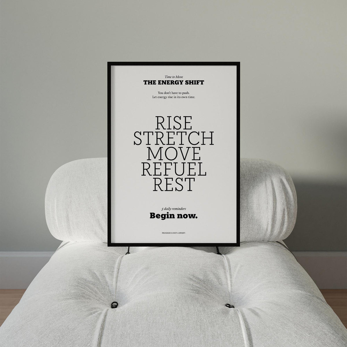 Framed print with motivational text in black on white leaning on a white cushioned chair