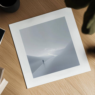 Gray and white wall art laid flat on a wooden surface with a black cup nearby