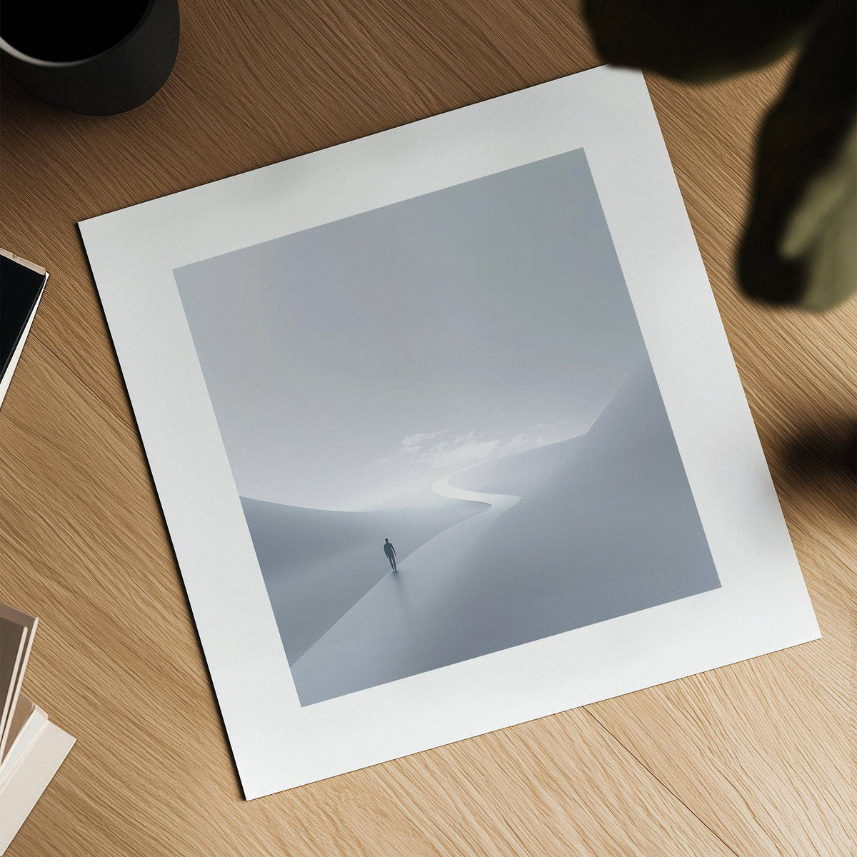 Gray and white wall art laid flat on a wooden surface with a black cup nearby