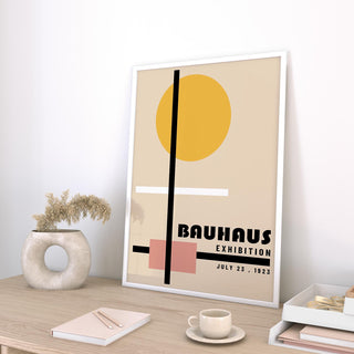 Print leaning on a desk of abstract geometric shapes in beige yellow and pink with a ceramic vase nearby