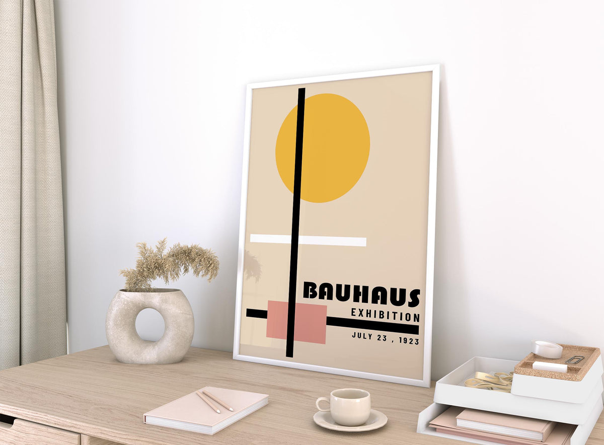 Print leaning on a desk of abstract geometric shapes in beige yellow and pink with a ceramic vase nearby