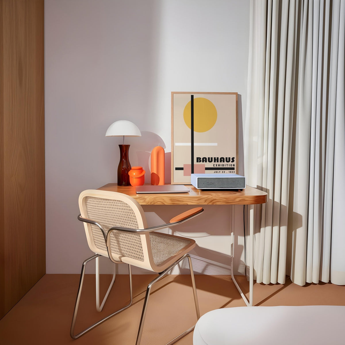 Office prints leaning on a wooden desk with a lamp and orange vases in a neutral room